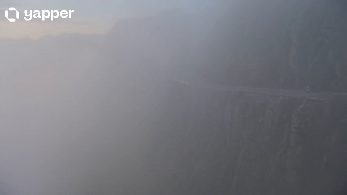 Motorbike carving a fog-covered mountain cliff road