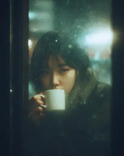 Moody cafe portrait through a rain-covered window