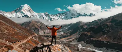 Lone traveler celebrating atop a boulder before Himalayan peaks