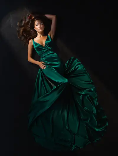 Overhead studio portrait in emerald satin gown on dark floor