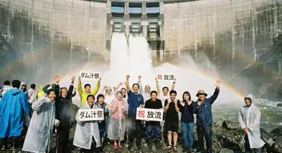 Fictional crowd celebrating under a released dam waterfall