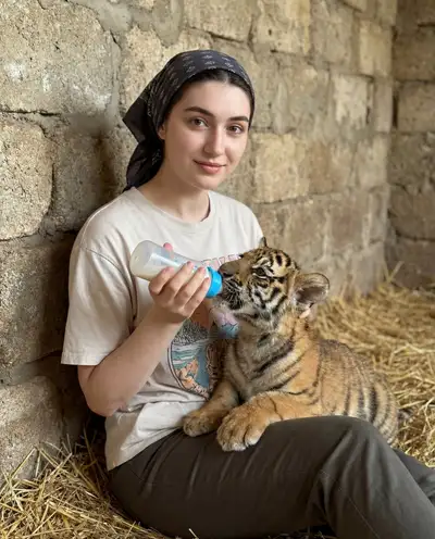 Lifestyle portrait of a woman bottle-feeding a tiger cub
