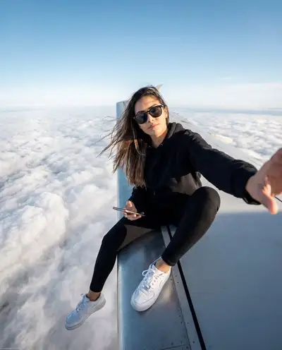 Confident Selfie on an Airplane Wing Above the Clouds