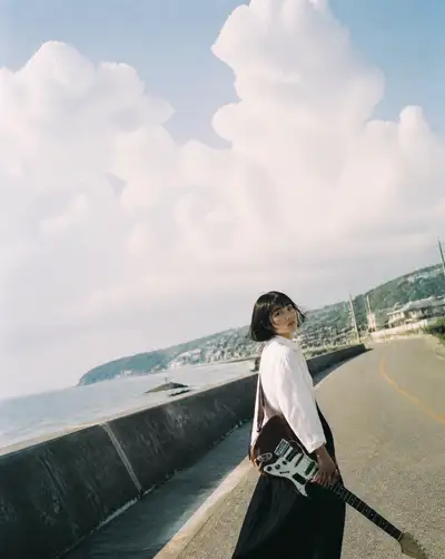 Japanese Woman with a Vintage Guitar on a Seaside Road