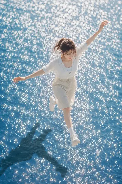 Sunlit portrait of a woman walking across shimmering water