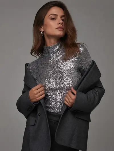 Editorial fashion shot of a blazer sliding off a sequined top