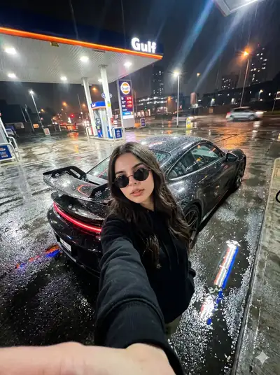 Selfie de nuit sous la pluie dans une station-service avec voiture de sport