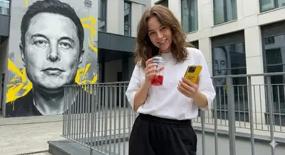 Playful street portrait with a drink cup in front of a mural