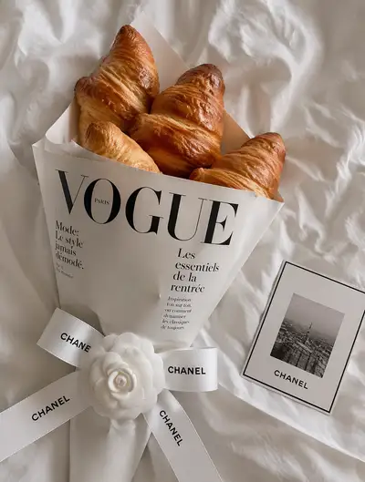 Croissants wrapped in Vogue and Chanel branding flat lay