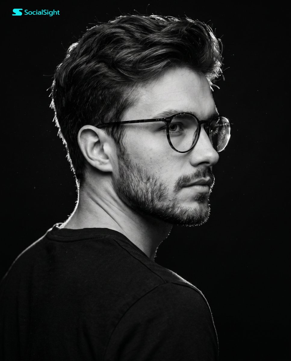 A dramatic high-contrast studio portrait of a young man with dark messy hair