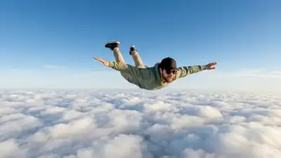 空の雲の上を水平に飛ぶ男性