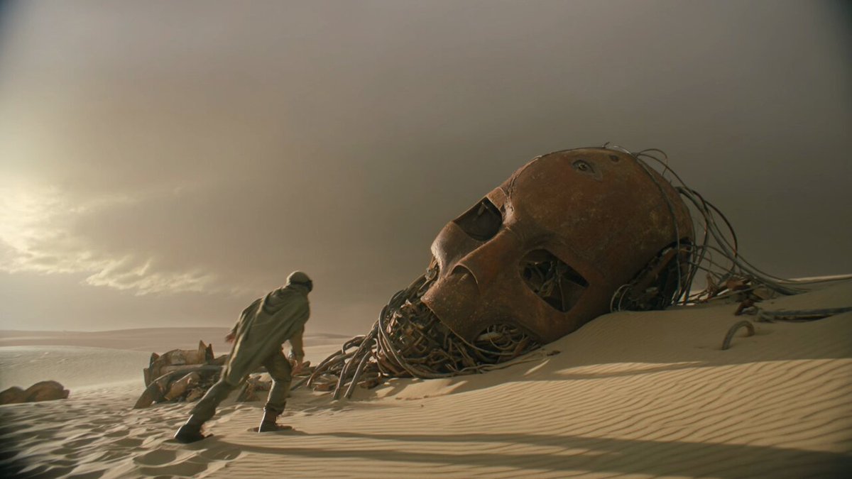 Desert scavenger climbing through a rusted mech head before a sandstorm