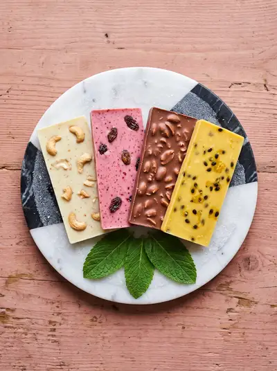 Quatro barras de chocolate gourmet em um prato de mármore com hortelã