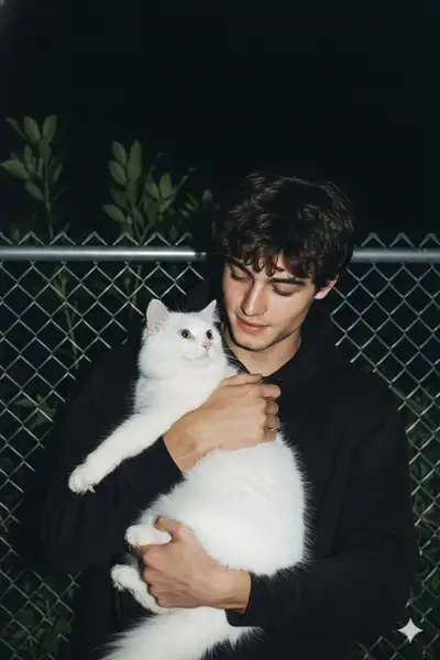 Candid night flash photo of a man affectionately holding a fluffy cat