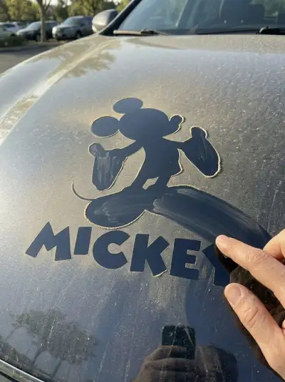 Logo revealed by finger-wiped dust on a car hood