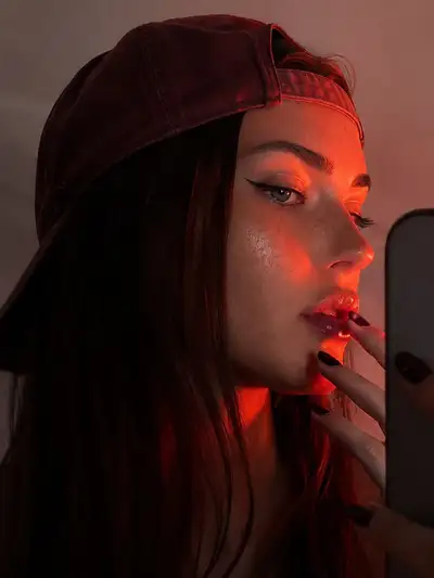 Selfie de perfil con gorra y luz roja dramatica de borde