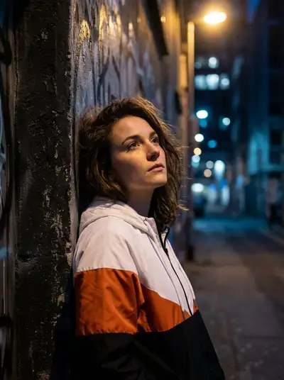 Pensive woman in a color-block jacket under dramatic light
