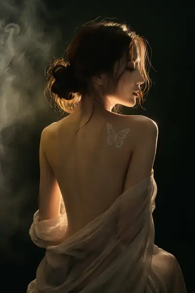 Low key portrait of a woman's back wrapped in sheer gauze