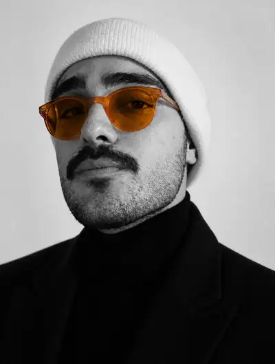 Black and white studio headshot with color-pop glasses