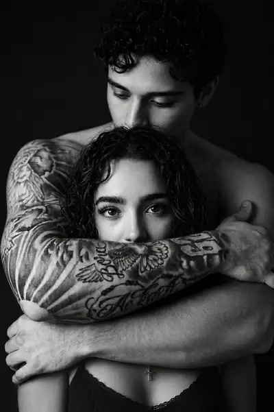 Retrato de casal monocromático com detalhe de tatuagem e abraço protetor