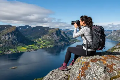 Woman photographing a Scandinavian fjord landscape from a rock ledge