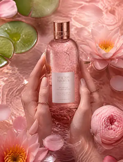 Luxury bath gel bottle held in hands submerged in pink water