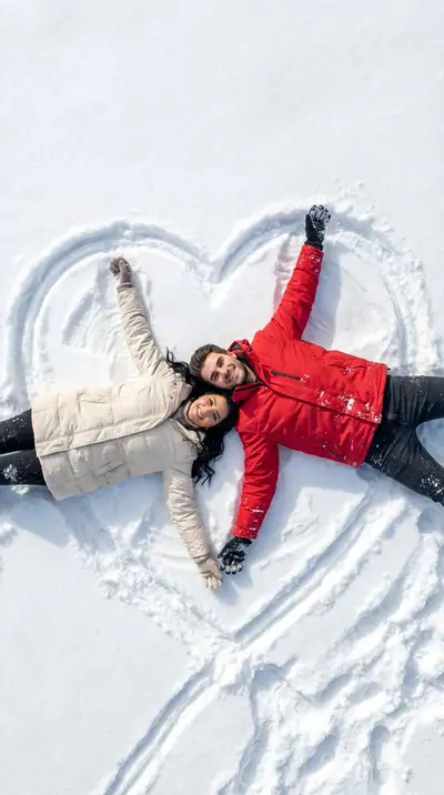 新雪に刻まれたハートの中で寄り添うカップルの冬の俯瞰写真